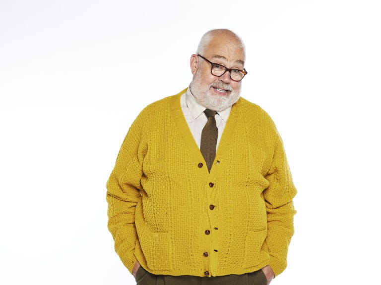 Cliff Parisi standing in a yellow cardigan