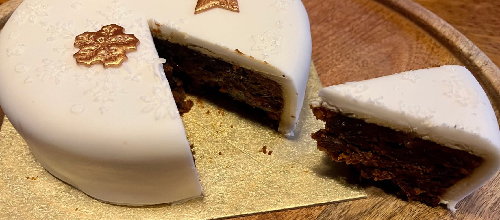 An Aldi Christmas cake on a plate with a slice cut out of it