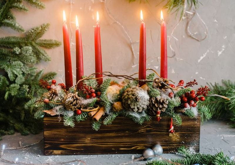 A Christmas display with five candles and winter natural foliage