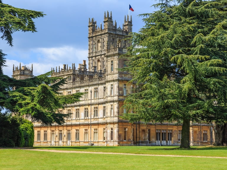 Highclere Castle, a Jacobethan style country house in Hampshire, visible between two ancient trees