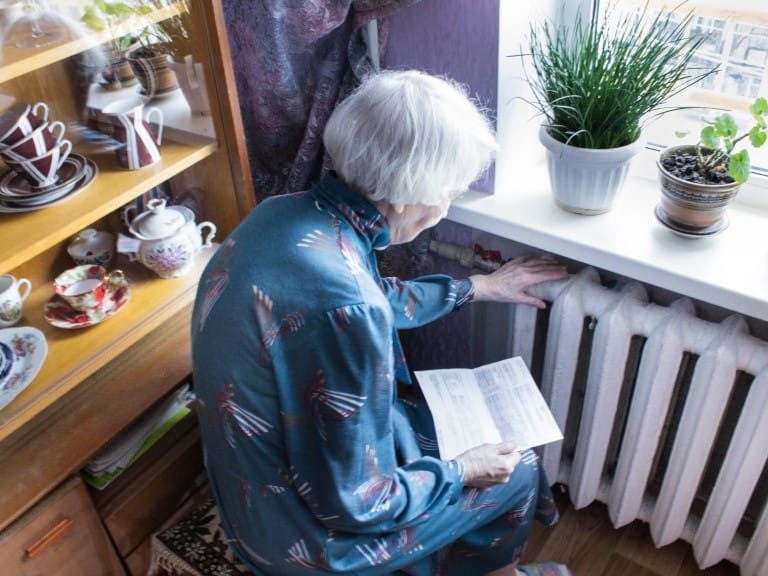 An elderly woman touching her radiator