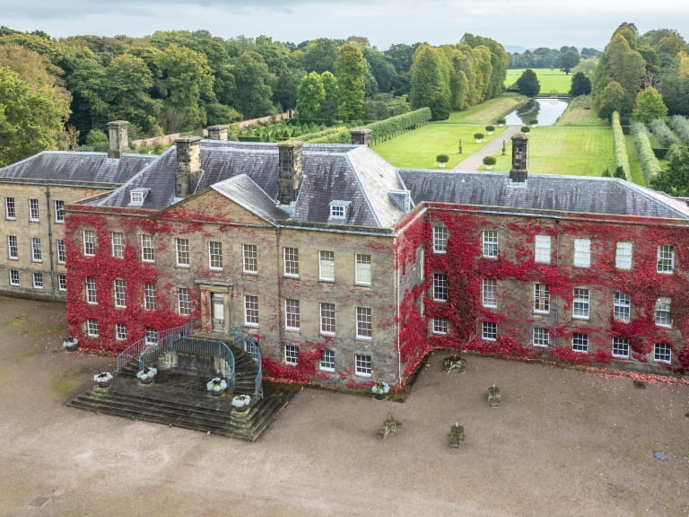 The impressive frontage of Erddig Hall, Wales, covered in vibrant red ivy