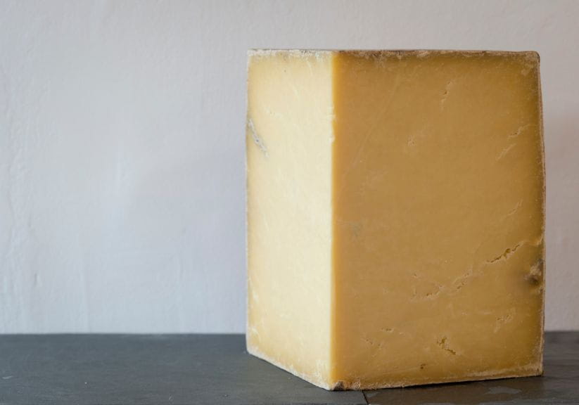 A chunk of montgomery cheddar cheese with a dark rind