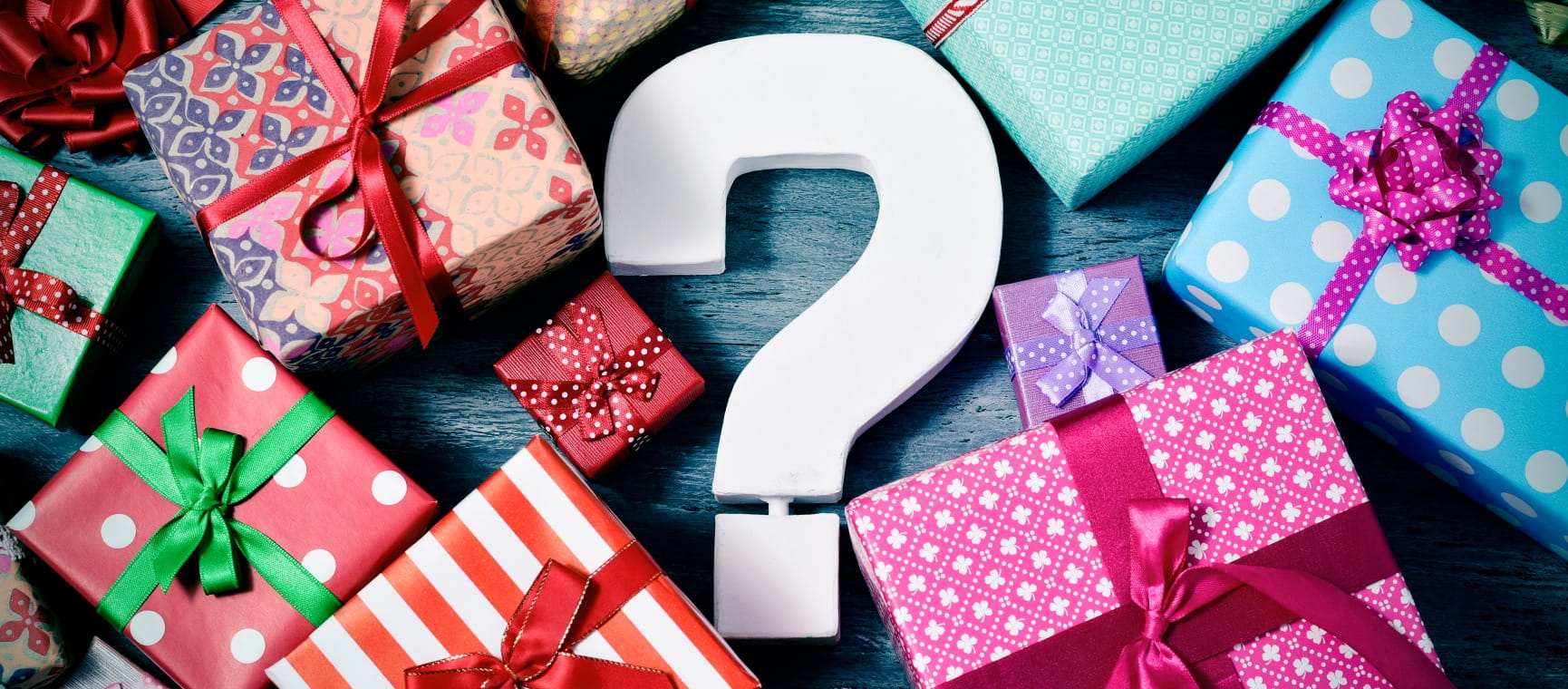 A white question mark surrounded by wrapped Christmas gifts