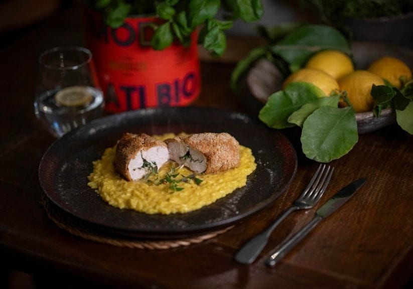 a plate of chicken kiev with risotto on a wooden table