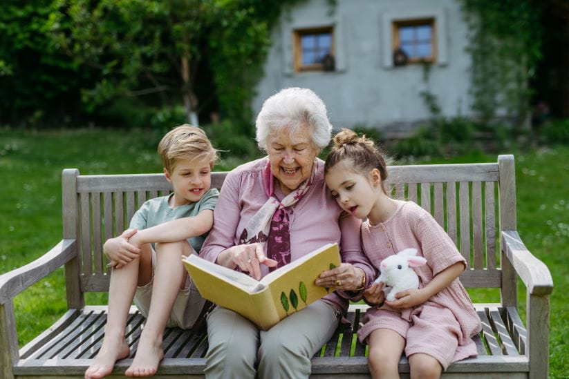 Grandma reading to kids on a bench