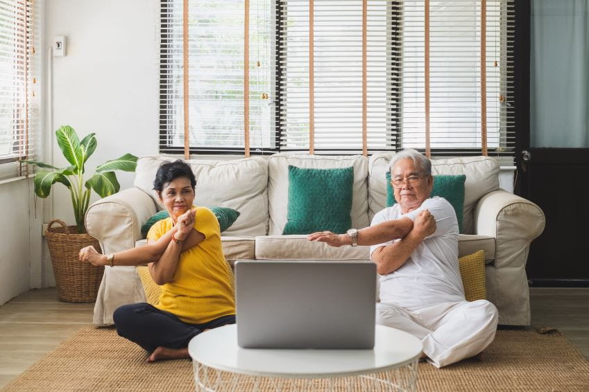 Man and woman in the lounge doing a Pilates class online