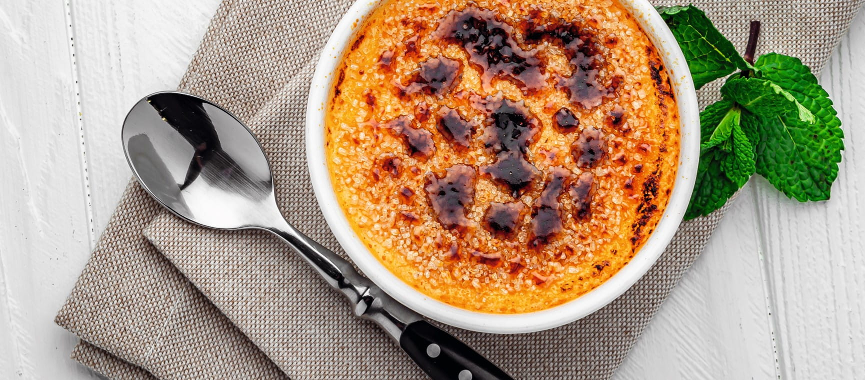 A bowl of creme brulee and a spoon taken from above