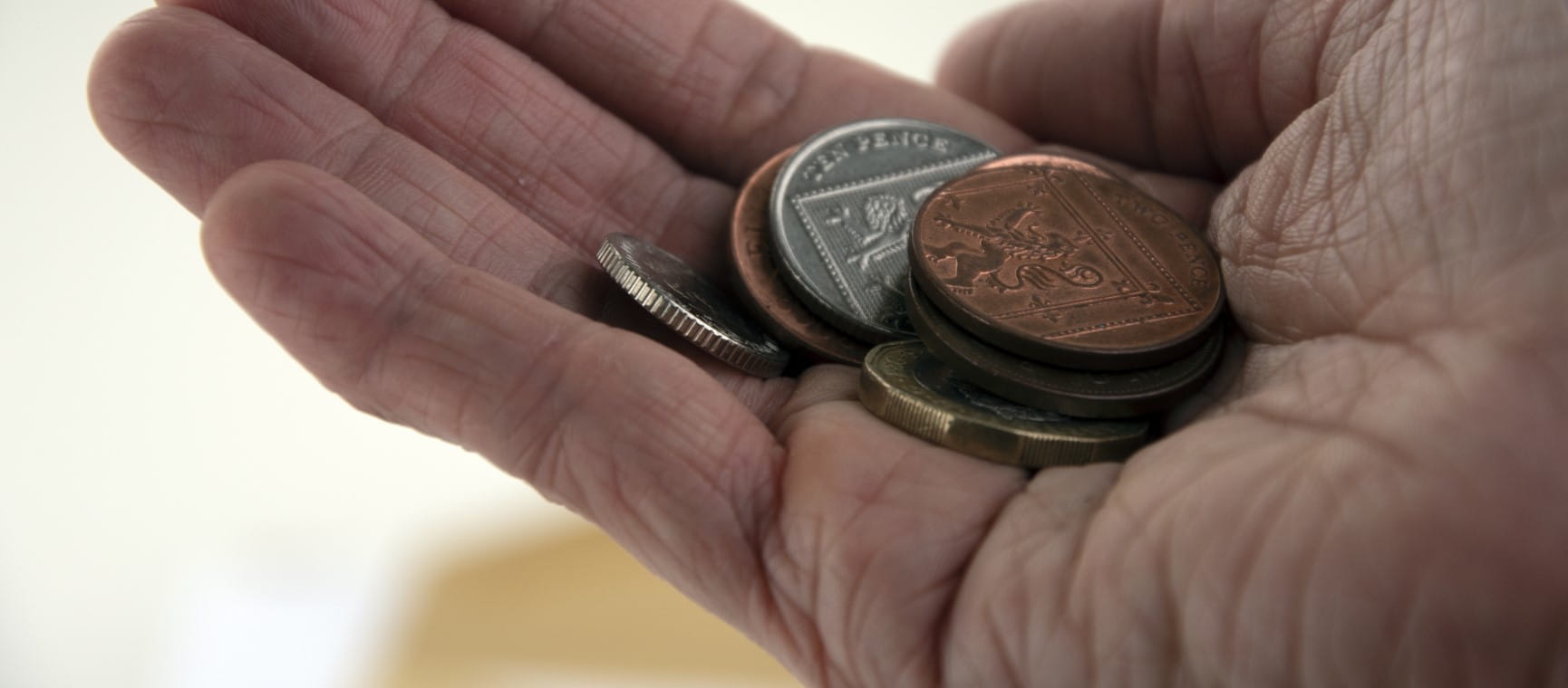 Collection of British coins in open hand to represent poverty in retirement | Getty/Bryony van der Merwe