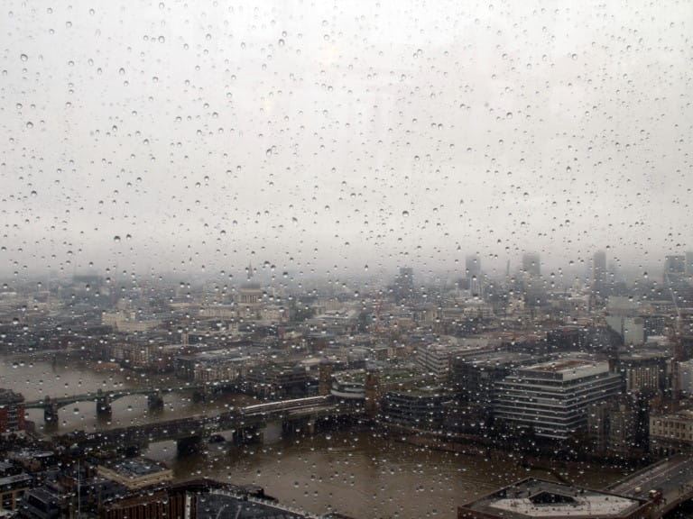 A gloomy photograph of raindrops on a glass window looking out over London and the Thames | Getty/Wirestock 