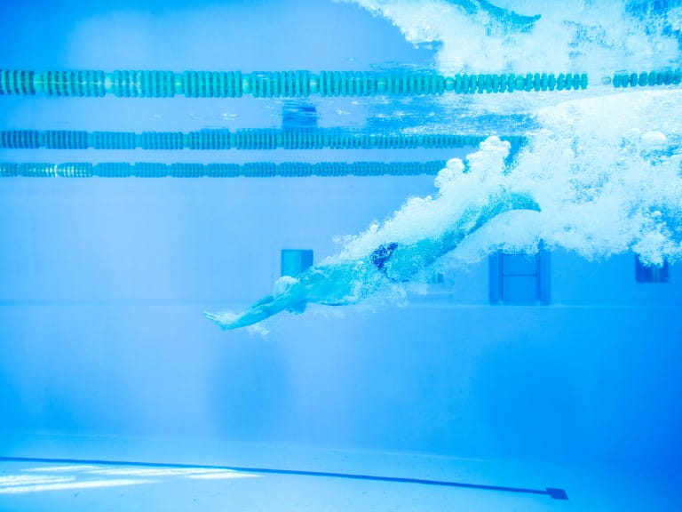 An older man dives into the pool, underwater photo | Getty/Halfpoint