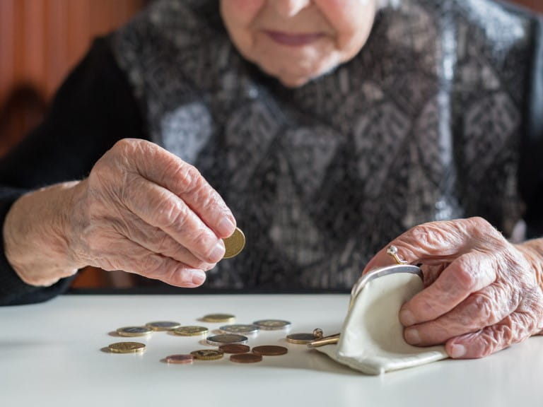 An older lady counts out her pension | Getty/kasto80