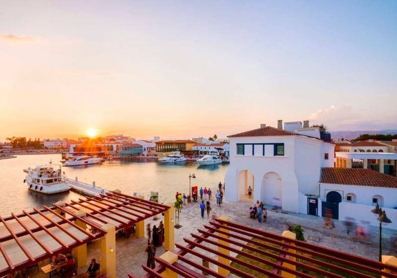 sunset over Limassol harbour in Cyprus with white houses and the bay behind