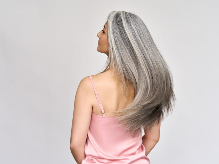Back view of mature lady with beautiful long gray natural coloring vibrant silky hair | Getty/insta_photos