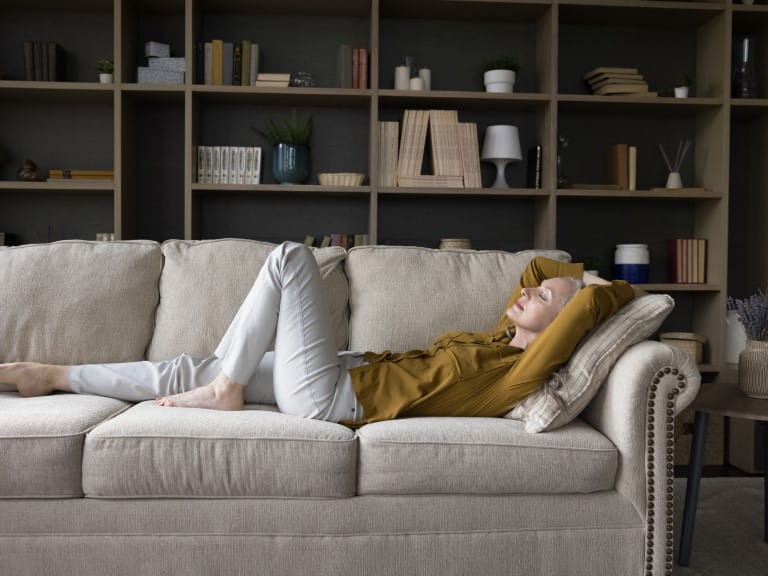 Mature woman lying on a sofa to combat dizziness |Getty/fizkes