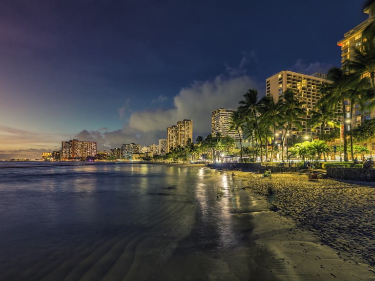 Night panorama of Waikiki Beach with sand and palm trees in Honolulu, Hawaii | Getty/marchello74