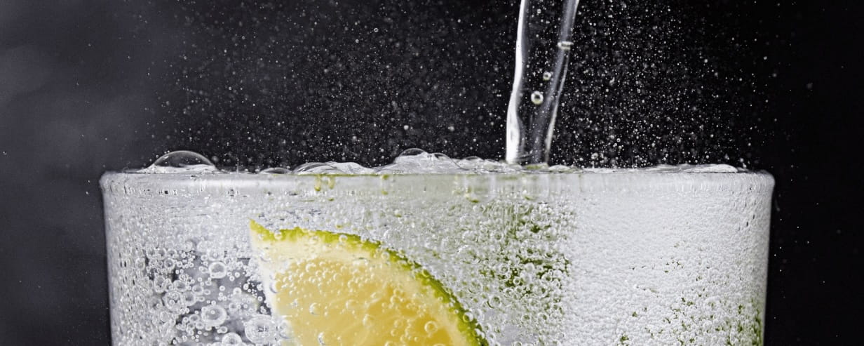 Sparkling water being poured into a glass with lemon