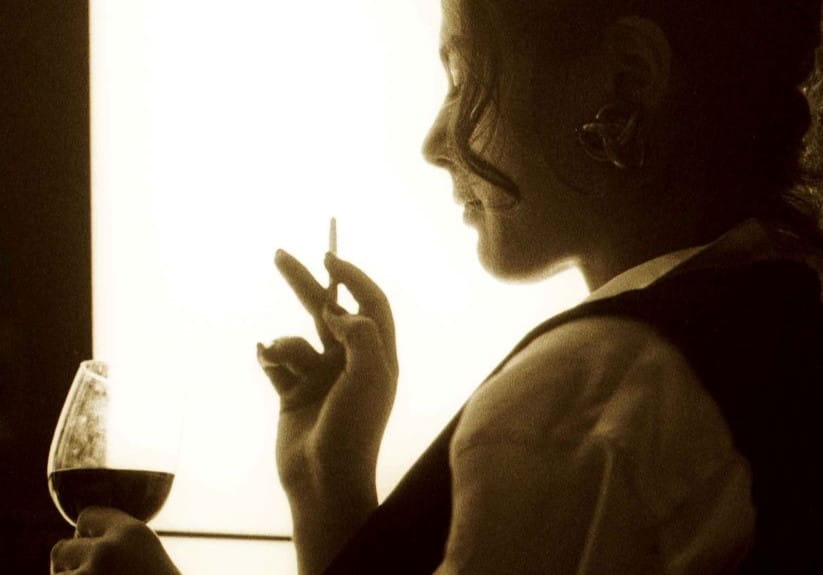 Woman with a cigarette and glass of wine in silhouette