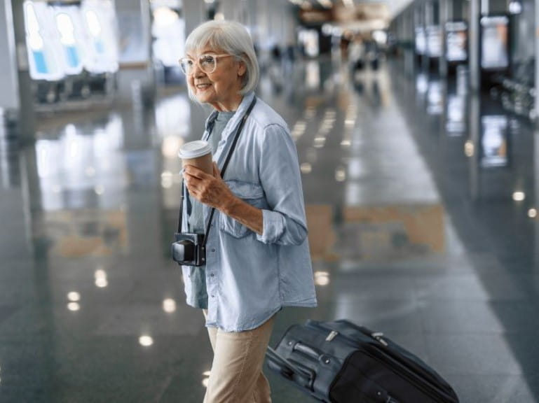 Stylish senior lady walking with camera at airport