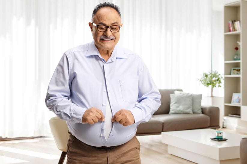 a overweight man measuring his waistline