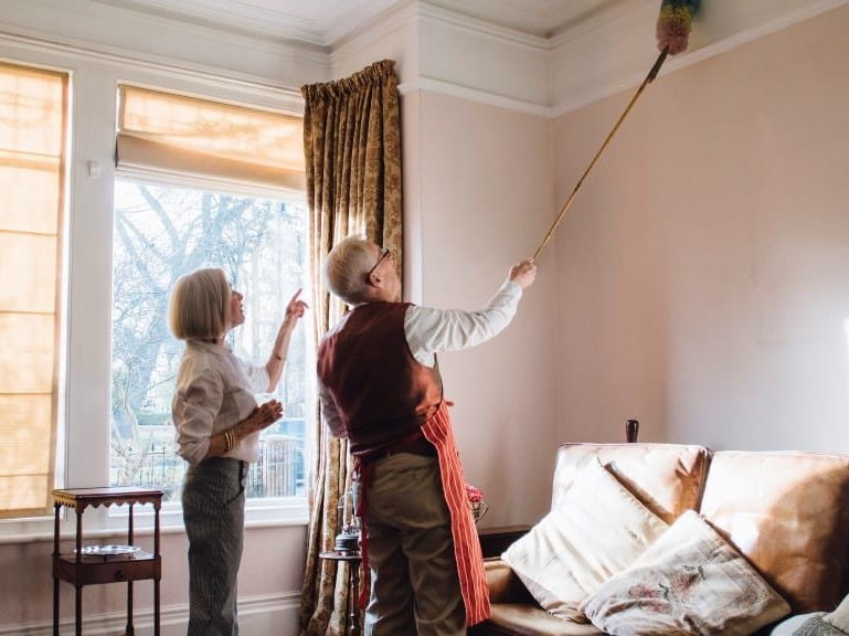 couple cleaning the house with a feather duster