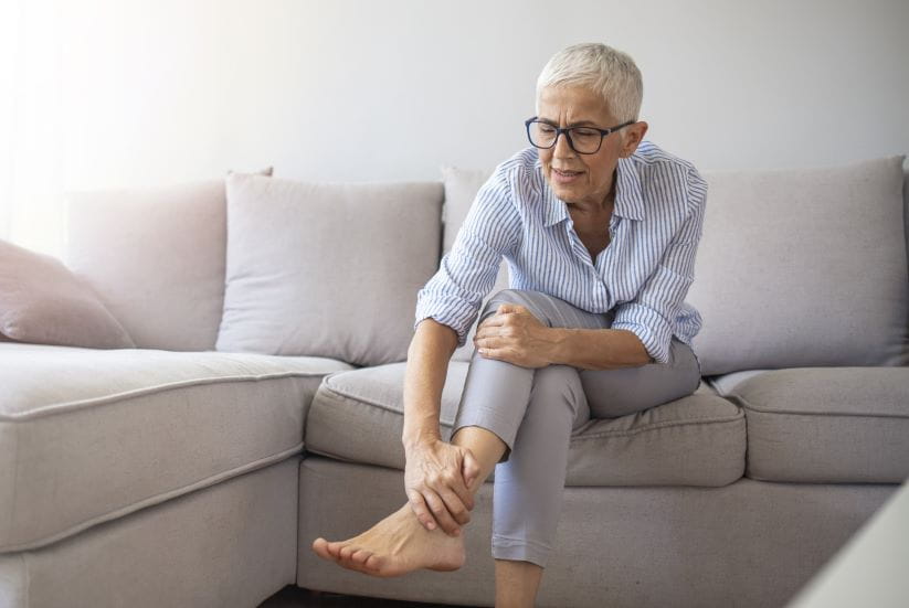 A woman sat on a sofa clutching her ankle