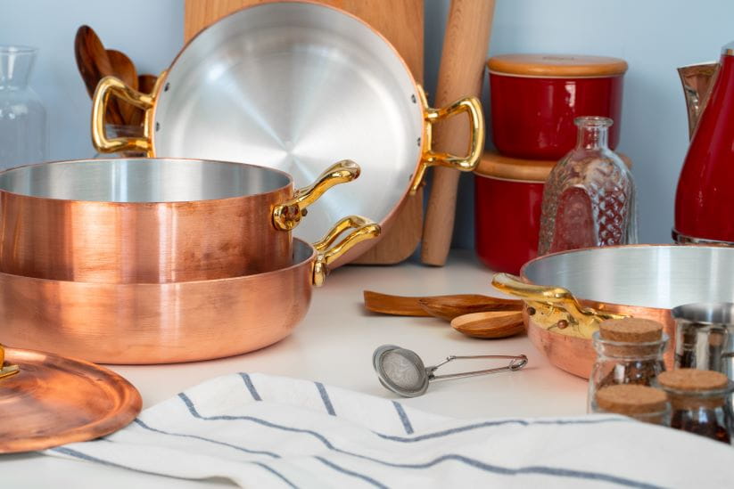 a selection of copper pans on a table top
