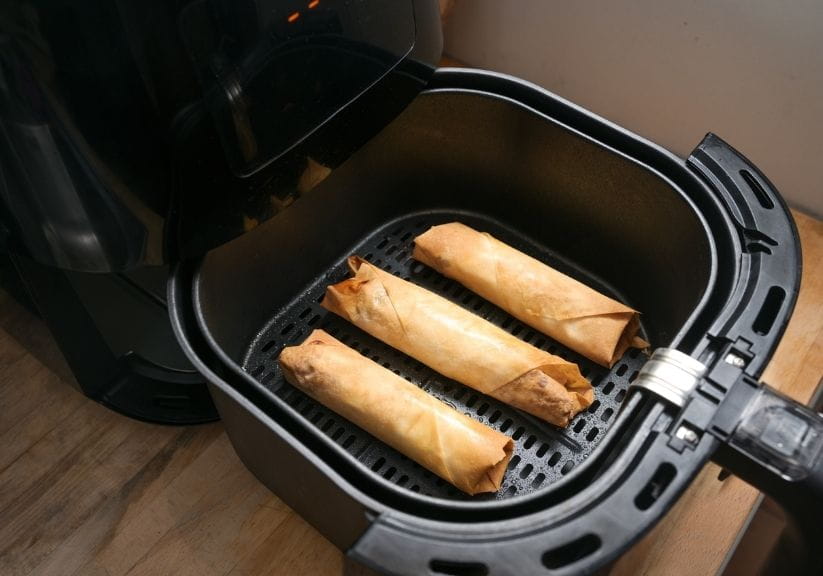 three pancake rolls in the drawer of an air fryer