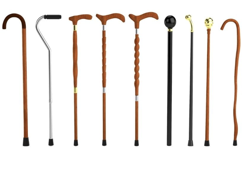 A selection of walking sticks and canes in a row on a white background