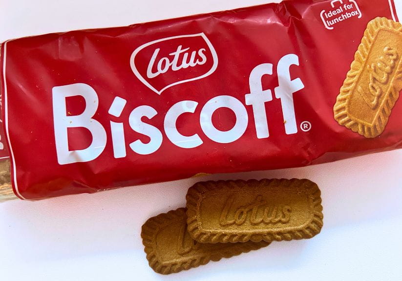 A packet of Biscoff biscuits with two Biscoff biscuits by the side