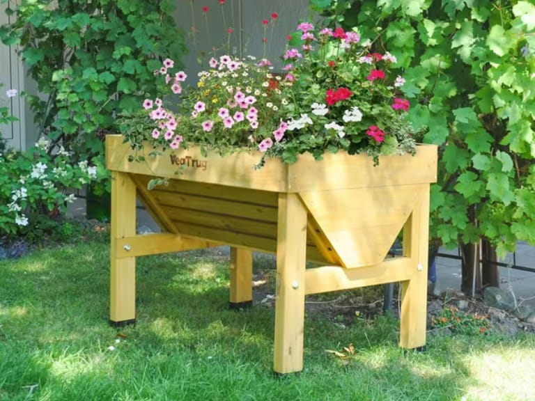 A raised wooden planter containing pink flowers