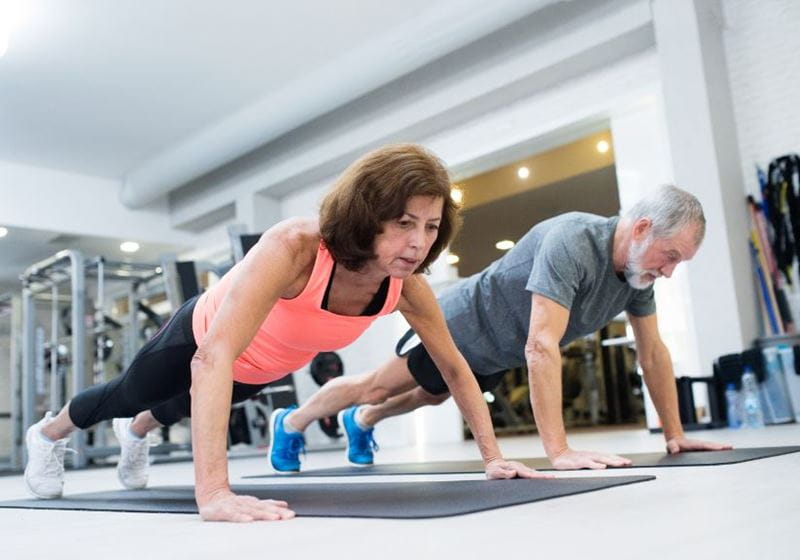 Man and woman doing a pushup in a gym