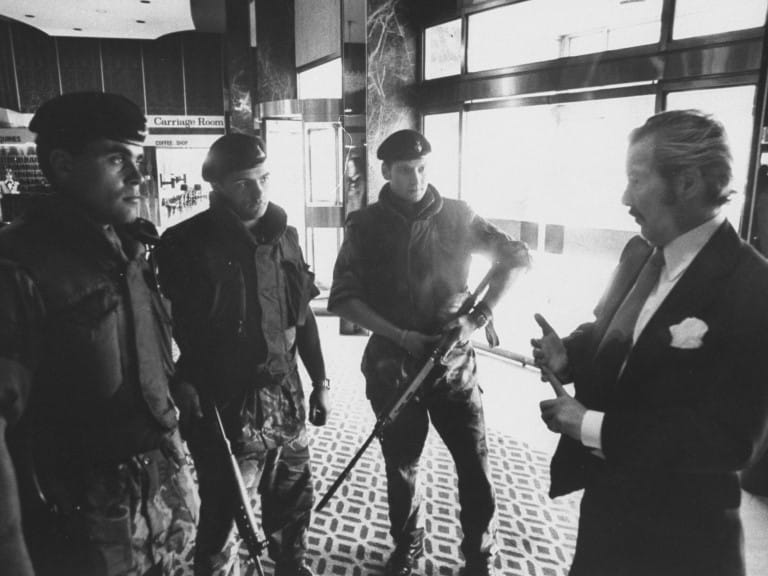 A hotel lobby with armed British soldiers inside