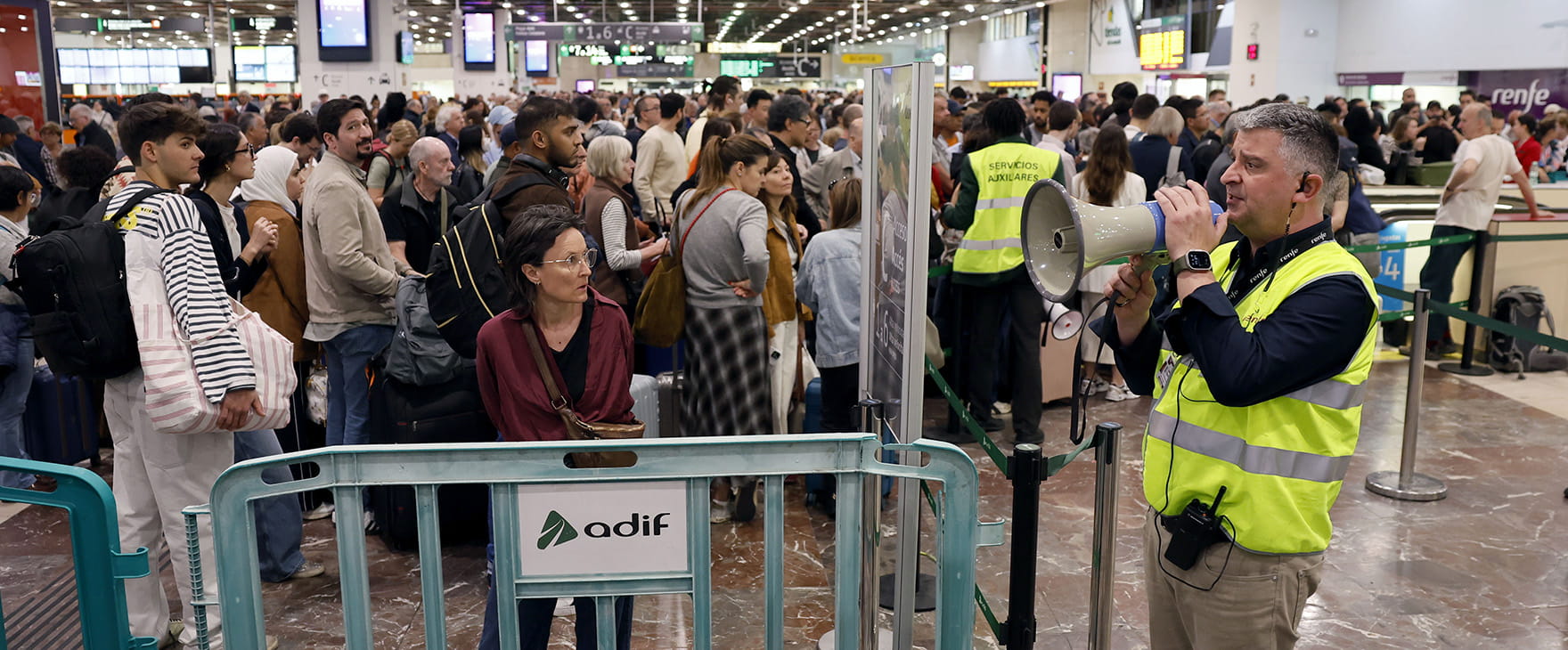 queues of stranded people at a train station in spain