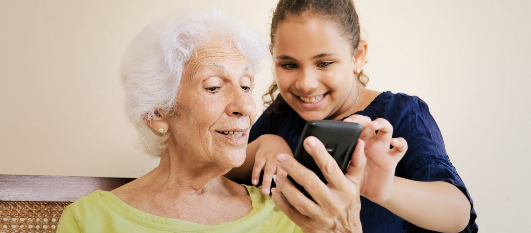 A teenager shows their grandmother how to use a mobile phone
