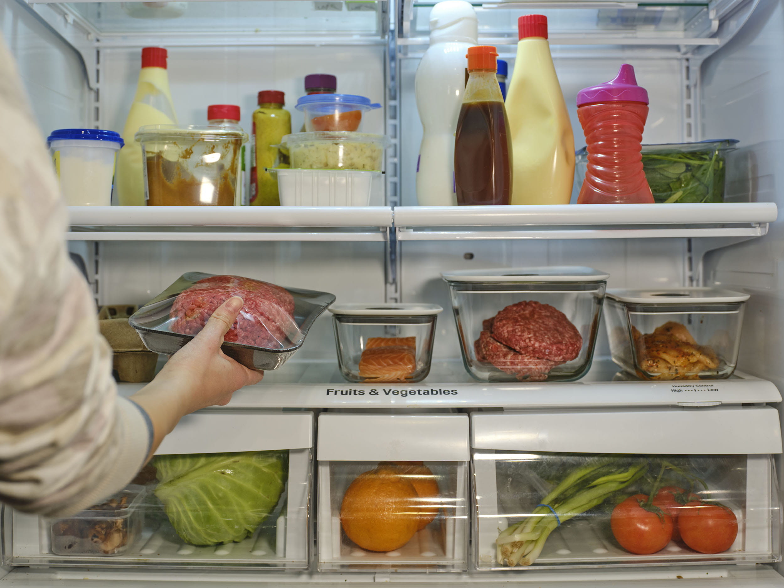 Woman taking out some meat from her fridge