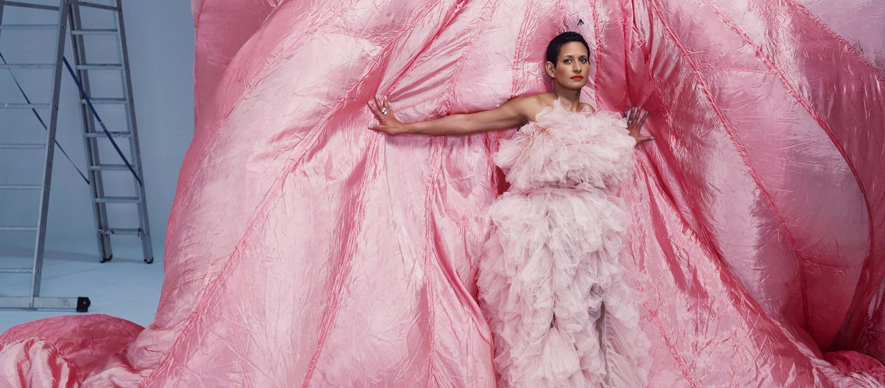TV and radio presenter Naga Munchetty poses in a pink dress against a billowing pink fabric for a Saga Magazine photoshoot