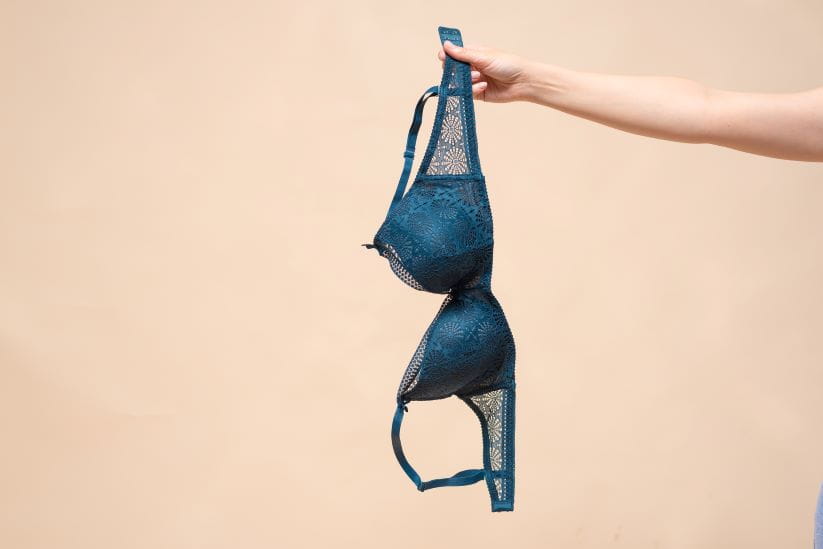 An arm in shot dangling a blue bra
