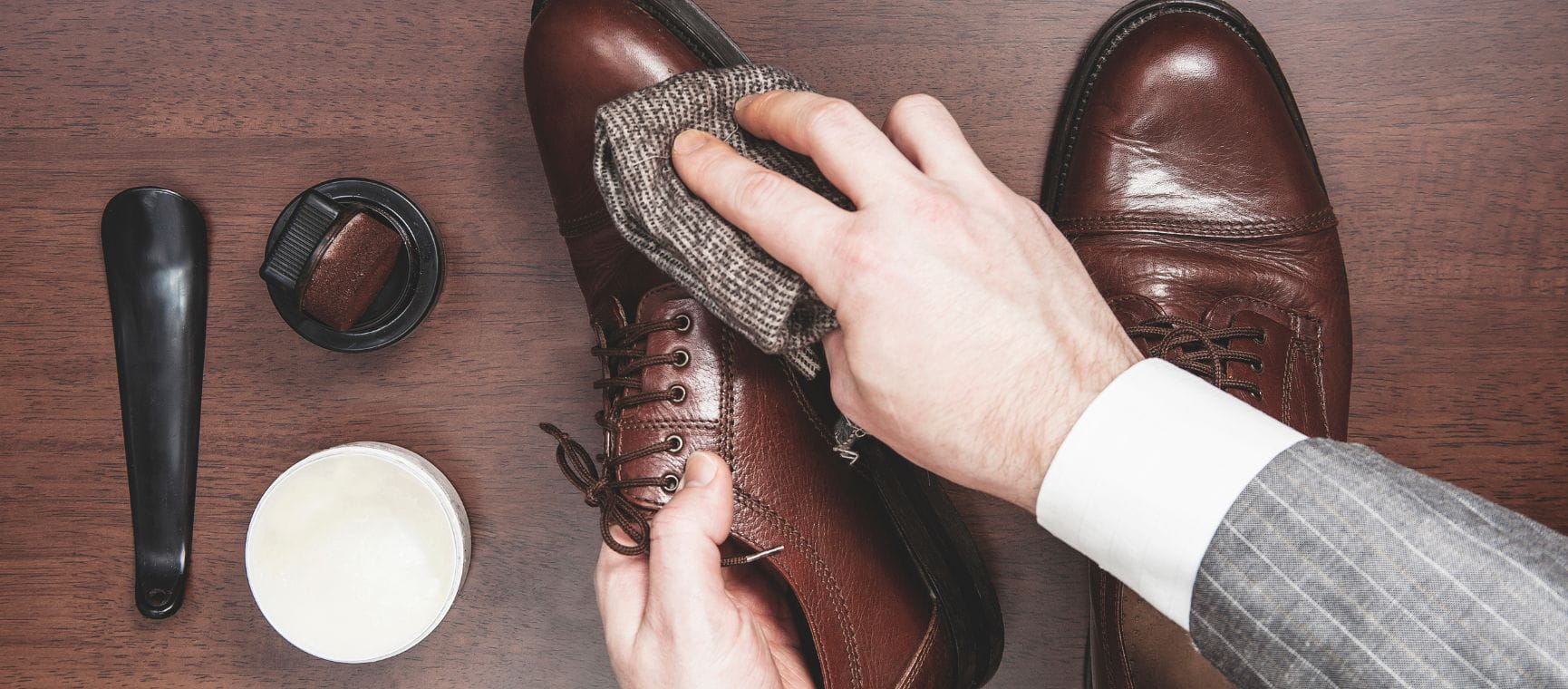A pair of hands cleaning a pair of brown leather boots