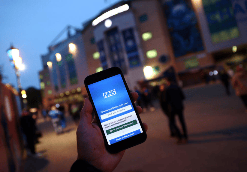 Someone holding up a phone with an nhs app on a dark evening