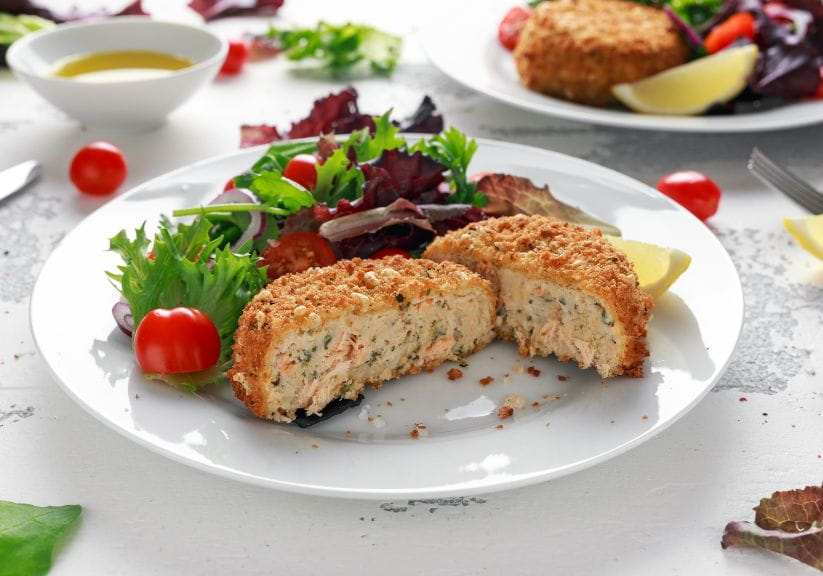 A salmon fishcake cut open on a plate