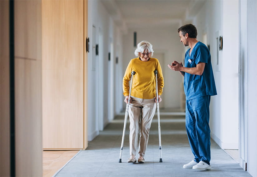 A nurse laughing with a woman after her successful surgery