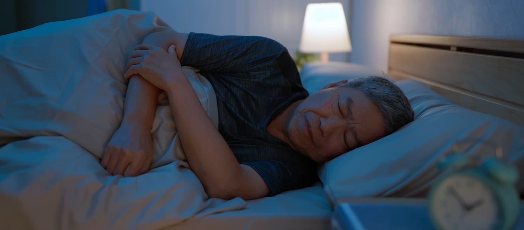 An older man sleeping poorly in bed