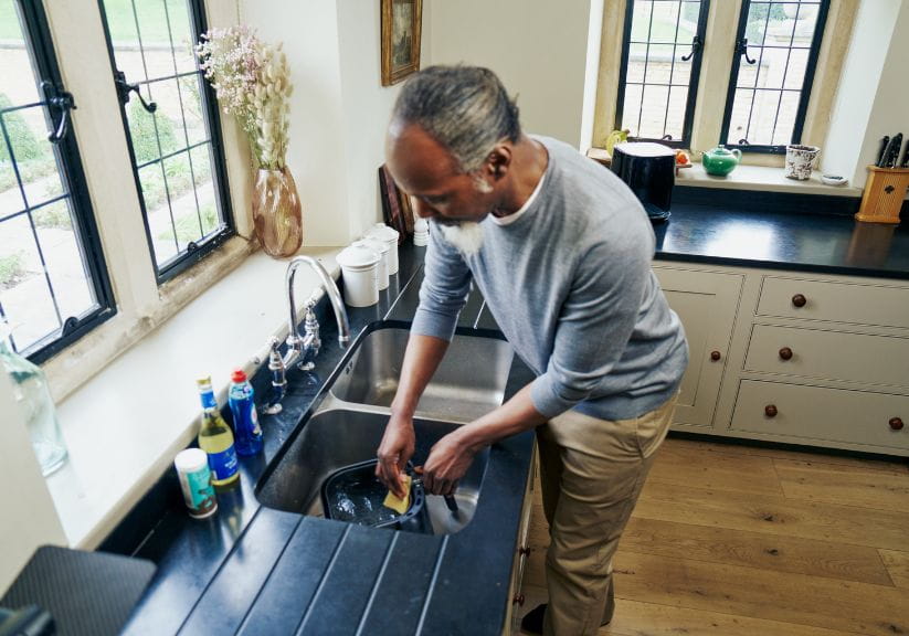 A man washes up an air fryer basket in the sink