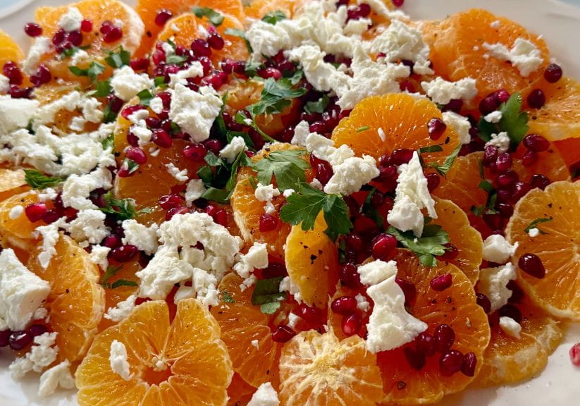 A close up of a salad made with oranges, feta cheese and pommegranates