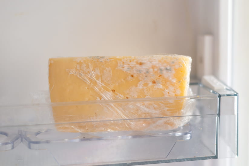 A block of cheddar cheese going mouldy in the fridge