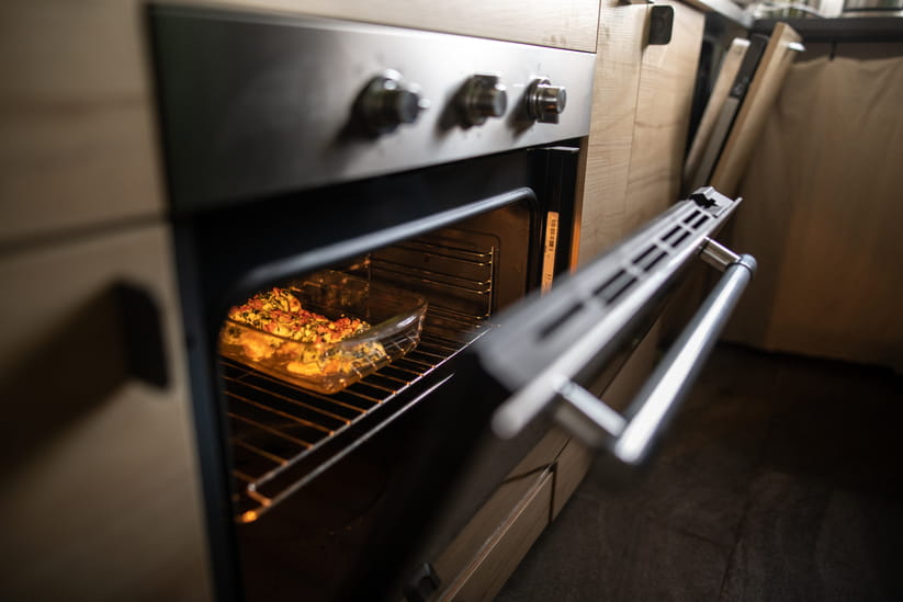 An oven door part open showing a small pie inside