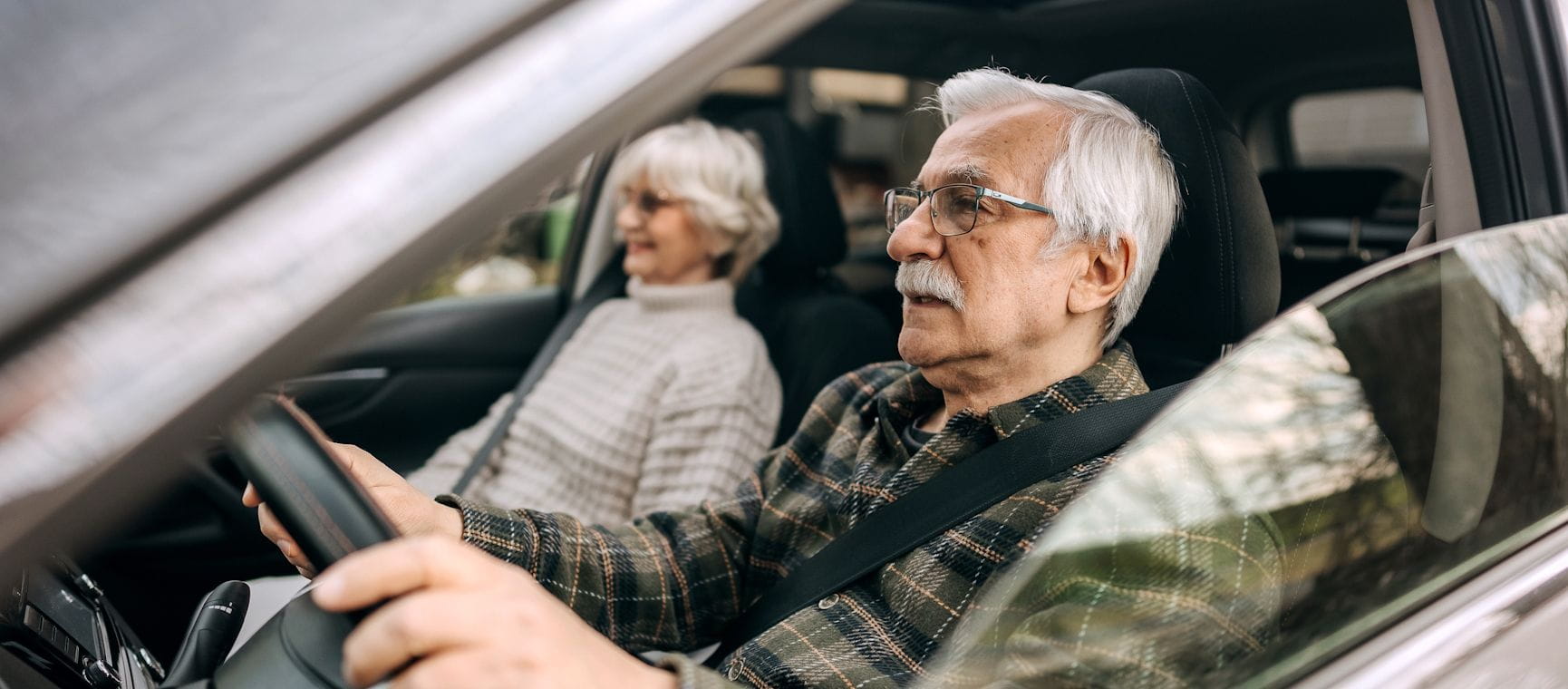 An elderly couple driving a car