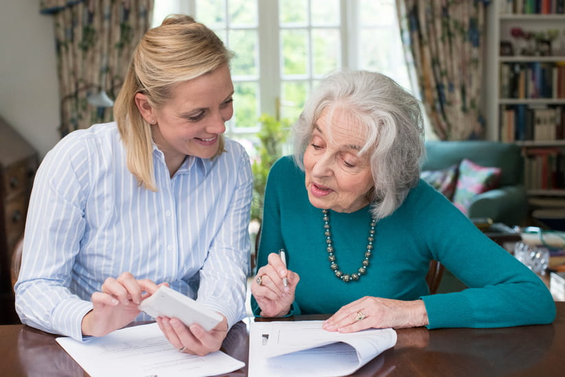 A younger woman and an older woman sat a desk looking at papers