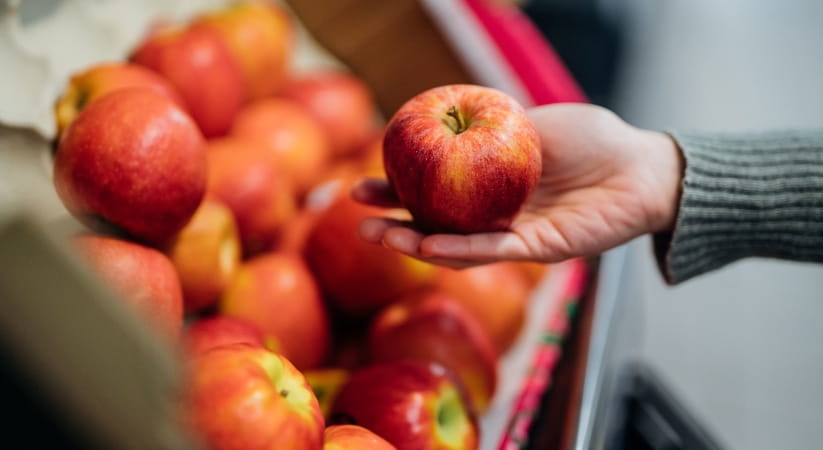 An apple being picked out of a display in a supermarket